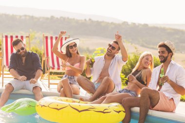 Havuz başında bir yaz partisinde bir grup arkadaş, yüzme havuzunun kenarında bacakları suyun içinde, bira içip eğleniyorlar.