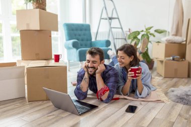 Birbirine aşık güzel genç bir çift birlikte yaşıyor, dizüstü bilgisayarla internette sörf yapıyor, internette daire dekorasyonu fikirleri arıyor.