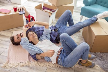 Birbirine aşık çiftlerin yeni evlerinin zemininde yatıp selfie çektikleri yüksek açılı bir manzara.