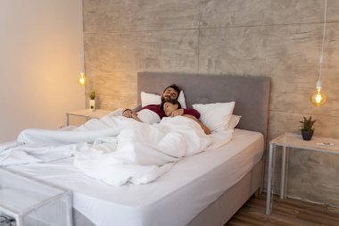 Güzel genç çift pijama giyiyor, yatakta uzanıyor, sarılıyor, uyuyor.