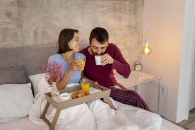 Güzel, genç ve aşık bir çift yatakta uzanıyor, sabahları dinleniyor ve kahvaltı yapıyorlar.