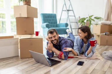 Birbirine aşık güzel genç bir çift birlikte yaşıyor, dizüstü bilgisayarla internette sörf yapıyor, internette daire dekorasyonu fikirleri arıyor.