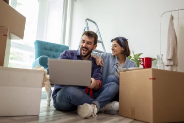 Güzel, birbirine aşık genç bir çift yeni dairelerinde karton kutuların arasında oturuyor, kahvaltı yapıyor ve dekorasyon fikirleri arıyor.