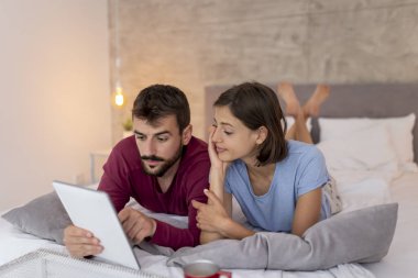 Sabahları pijama giyen, kahve içen ve tablet bilgisayarda internette sörf yapan güzel bir çift.