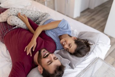 Aşık çift uyandıktan sonra yatakta yatıyor, sarılıyor, gülüyor ve birlikte vakit geçiriyorlar.