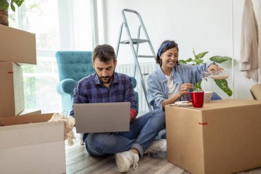 Birbirine aşık güzel genç bir çift yeni dairelerinde karton kutuların arasında oturuyor, kahvaltı yaparken eğleniyorlar.