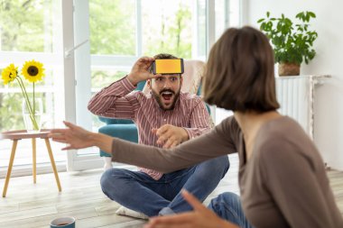 Çift evde sessiz sinema oynayarak eğleniyor, akıllı telefon uygulamasından gelen kelimeleri açıklıyor ve tahmin ediyor.