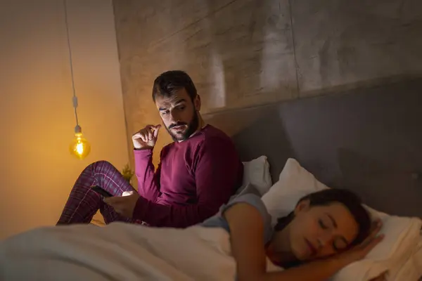 Hombre Escribiendo Mensaje Texto Teléfono Inteligente Mientras Novia Está Dormida —  Fotos de Stock
