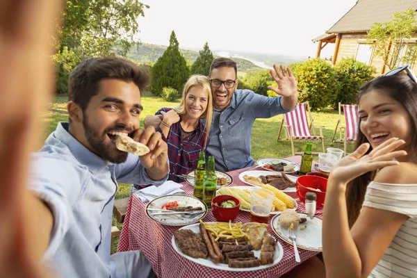 Bir grup arkadaş arka bahçede barbekü partisi veriyor, selfie çekerken eğleniyorlar. Ortadaki çifte odaklan.
