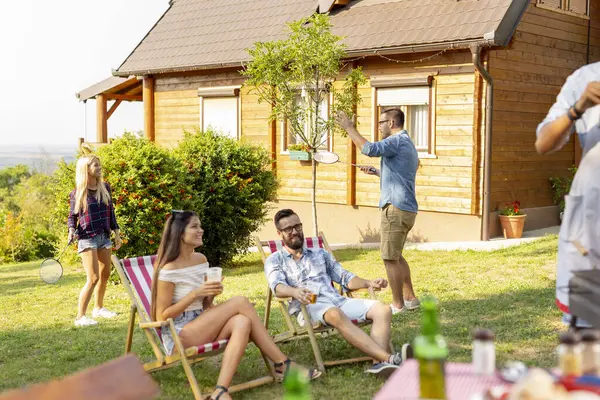 一群朋友在后院举行烧烤派对 喝啤酒 打羽毛球 在阳光灿烂的夏日玩乐 — 图库照片