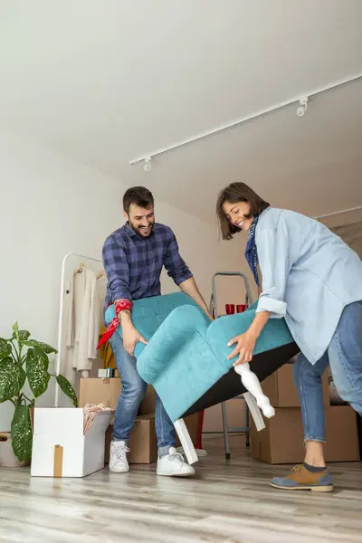 愛するカップルは一緒に移動し アームチェアを運んで 新しい家具の配置を設定しながら楽しんでいます — ストック写真