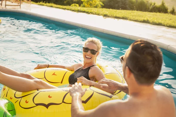 Havuz başında bir yaz partisinde aşık bir çift, güneşleniyor ve eğleniyor; kız ananas şeklinde bir şişme yatakta havuzda yüzüyor. 