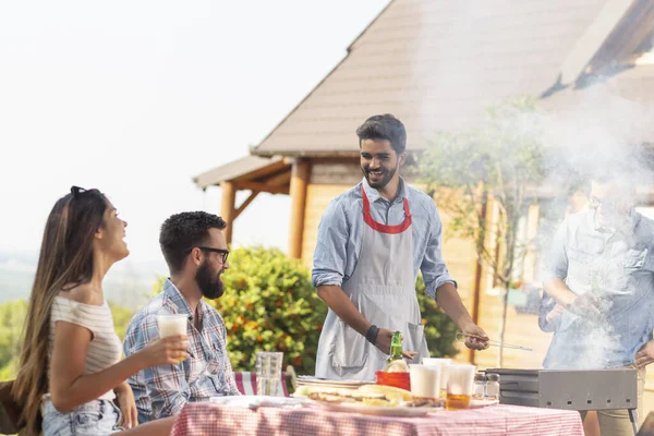 Bir grup arkadaş arka bahçede barbekü yapıyor, bira içiyor ve güneşli bir yaz gününde eğleniyorlar.