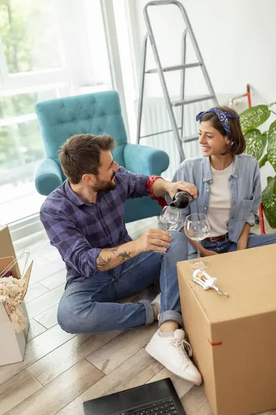 Yeni bir daireye taşınıp bir şişe şarap açarak kutlama yapan genç ve güzel bir çift.