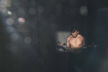 Spor salonunda çalışan, maske takan ve ağırlık kaldıran kaslı vücut geliştirici.