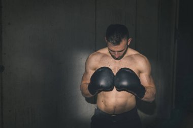 Formda kaslı boksör boks eldiveni giyiyor, yarışmaya hazırlanıyor.