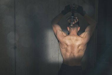 Spor salonunda ağırlık kaldıran kaslı vücut geliştirici.