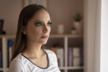 Evdeki pencerenin kenarında duran güzel genç bayan, dinleniyor ve boş zamanlarının tadını çıkarıyor.