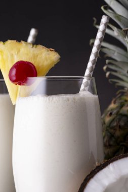 Koyu rom, ananas suyu ve hindistan cevizi kremalı, ananas dilimleri ve maraska sosuyla süslenmiş iki bardak pina colada kokteyli.