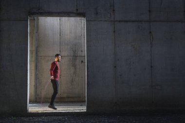 Atletik, kaslı adam atlama halatlarıyla çalışıyor. Sporcu atlama ipi kullanıyor, spor salonunda sıkı çalışıyor, kardiyo egzersizleri yapıyor.