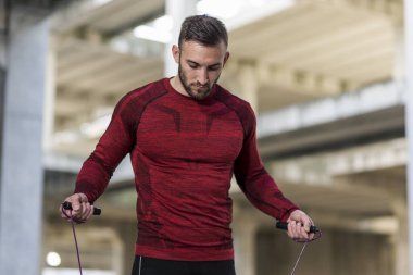 Atletik, kaslı bir adam ip atlama kardiyo çalışması yapıyor.