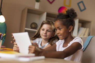 İki ilkokul öğrencisi tablet bilgisayar kullanarak çalışıp ödev yapıyor. Eğitim kavramında modern teknolojilerin kullanımı