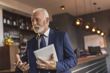 Kıdemli işadamı modern ofis binası restoranında toplantı yapıyor iş ortağıyla sohbet ediyor ve tablet bilgisayar kullanıyor.
