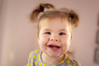 Dokuz aylık güzel bir kızın portresi gülümseyen ve komik suratlar yapan.