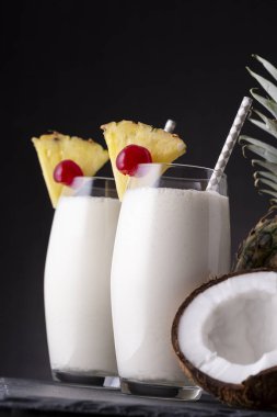 İki bardak koyu rom, ananas suyu ve Hindistan cevizi kremalı, ananas dilimleri ve maraska sosuyla süslenmiş pina colada kokteyli.