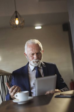 Bir restoranda kıdemli işadamı, tablet bilgisayarda çalışıyor, kızgın ve hoşnutsuz.