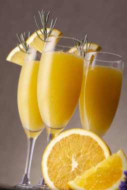 Şampanya bardaklarında Mimosa kokteylleri portakal suyu ve lavanta yaprakları ve portakal dilimleriyle süslenmiş köpüklü şarap.
