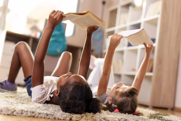 Две Маленькие Девочки Лежат Полу Игровой Комнате Читают Книги Школы — стоковое фото