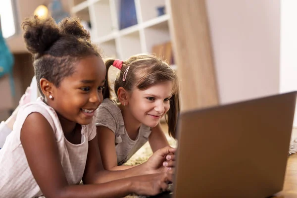 Две Маленькие Девочки Лежат Полу Игровой Комнаты Смотрят Мультики Ноутбуке — стоковое фото