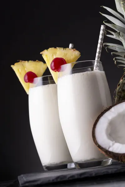 两杯带有黑朗姆酒 菠萝汁和椰子酱的菠萝鸡尾酒 配以菠萝片和马拉西诺樱桃 — 图库照片
