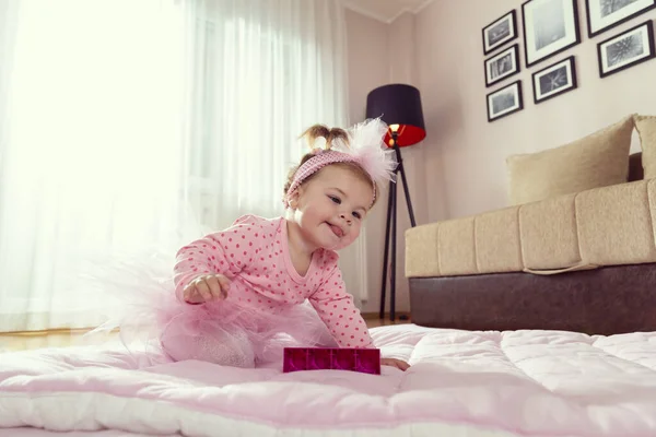 漂亮的小女孩穿着粉红短裙 爬到客厅的地板上 伸手去拿玩具 — 图库照片