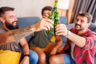 Bir grup erkek arkadaş evde vakit geçirip, kadeh kaldırarak ve bira içerek eğleniyorlar.