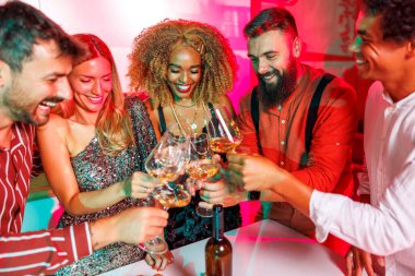 Bir grup neşeli genç arkadaş ev partisinde eğleniyor, kadeh kaldırıyor, şarap içiyor ve dans ediyor.