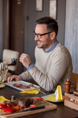 Restoranda buluşan bir adam öğle yemeği yiyor, şarap içiyor ve eğleniyor.