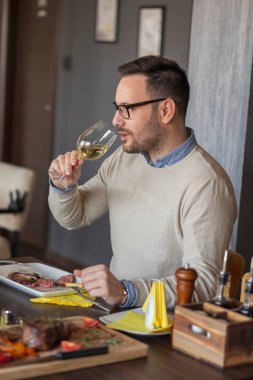 Restoranda buluşan bir adam öğle yemeği yiyor, şarap içiyor ve eğleniyor.