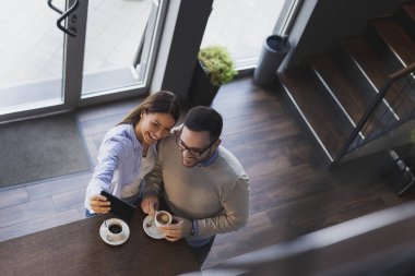Genç bir çiftin randevularına yüksek açılı bir bakış açısı. Lokanta tezgahının yanında durup selfie çekiyorlar.
