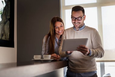 Lokanta tezgahında duran, kahve içen ve tablet bilgisayar kullanan güzel bir çift.