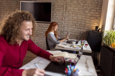 Modern ofiste çalışan erkek tasarımcı, çizim tahtası kullanarak çizim yapıyor; iş yerinde çalışan serbest çalışanlar