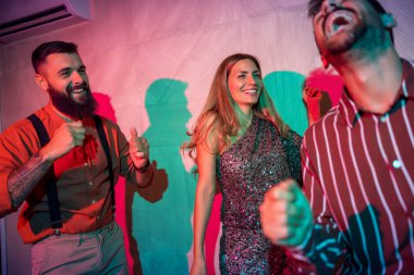 Bir grup neşeli genç arkadaş yeni yıl partisinde dans edip şarkı söylüyor.