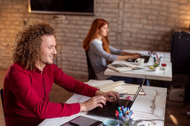 Modern bir ortak çalışma alanında çalışan programcı, dizüstü bilgisayarda kod yazma