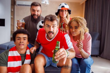 Bir grup futbol taraftarı, maçlarını kaçırıp maçı kaybettikten sonra TV 'de kızgın bir şekilde maçı izlerken eğleniyor.