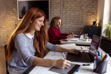 Modern bir ortak çalışma alanında yeni bir proje üzerinde çalışan tasarımcı; çizim tablosunda web tasarımcısı; modern bir ofiste çalışan genç iş adamları