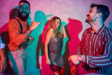 Bir grup neşeli genç arkadaş bir partide şarkı söyleyip dans ediyor.