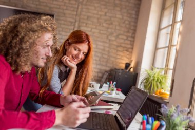 Web tasarımcıları modern ortak çalışma alanında yeni bir proje üzerinde çalışıyorlar; genç iş adamları modern ofiste birlikte çalışıyorlar