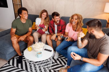 Evde video oyunu oynayarak eğlenen arkadaş grubunun yüksek açılı görünümü