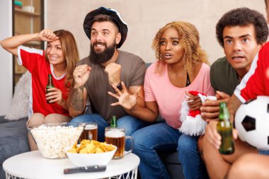 Bir grup arkadaş TV 'de futbol dünya şampiyonası maçı izliyor, tezahürat yapıyor, patlamış mısır yiyor ve bira içiyor.